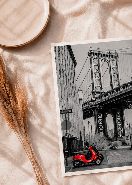 New York – Brooklyn Bridge punainen skootteri -valokuvajuliste aseteltuna vaalealle tekstiilille editorial-kuvassa.